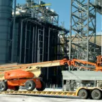 JLG 1250AJP boom lift driving onto truck trailer.
