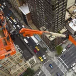 JLG 1850SJ Ultra Series telescopic boom lift raising workers for skyscraper maintenance.