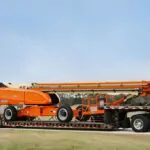 JLG 1850SJ Ultra Series telescopic boom lift traveling on a truck trailer.