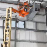 JLG 32E boom lift extended to ceiling for duct maintenance.