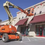 Worker tending to the side of a building in the bucket of a JLG 340AJ Articulating Boom Lift.