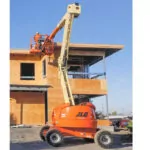 JLG 450AJ Articulating Boom Lift raising a worker to a building roof.