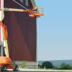 JLG 600AJ boom lift raising a worker near a barn.