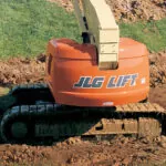JLG 660SJC telescopic crawler boom lift in rough dirt terrain.