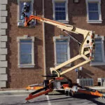 JLG T350 Tow-Pro boom lift raising a worker to provide building maintenance.