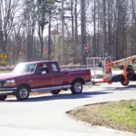 Red pickup truck towing JLG T350 boom lift.