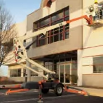 JLG T350 boom lift partially extended near a building.