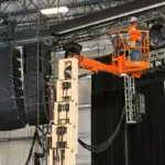 JLG 32E toucan mast boom lift raising a worker to provide maintenance on stage speakers.