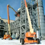 JLG 1200SJP ultra series telescopic boom lifts raising workers to provide outdoor facility maintenance.