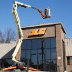 JLG X430AJ boom lift extended over JLG building.