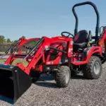 Mahindra eMax20S sub-compact tractor parked on gravel road.