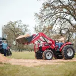 Mahindra 2638 compact utility tractor: bucket raised, transporting dirt.