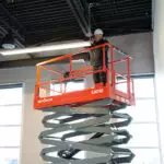 Skyjack SJ4740 DC Scissor Lift lifting operator to building ceiling.
