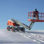 Operator driving Skyjack SJ66 T+ telescopic boom through snow.