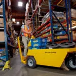 Taylor-Dunn SC-90 Stock Chaser utility vehicle carrying materials through warehouse.