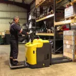 Combilift Combi-PPT-HC pallet mover and operator grabbing a pallet in warehouse.