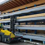 Combilift SLE 11000 multi directional sideloader electric forklift lifting lumber outdoors.