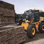 JCB 407 Wheel Loader stacking pallets in lumber yard.