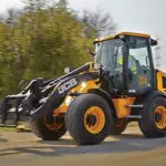 JCB 407 Wheel Loader driving down dirt road.