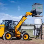 JCB TM-320 articulated telescopic handler transporting agriculture equipment.