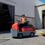 Taylor-Dunn C-426 Tow Tractor utility vehicle hauling industrial carts.