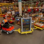 Taylor-Dunn C-426 Tow Tractor utility vehicle hauling industrial carts in warehouse.