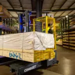 Combilift COMBI-MR4 dynamic multi-directional forklift carrying pallet of lumber in warehouse.