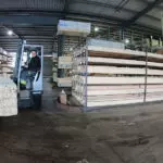 Combilift COMBI-MR4 electric forklift transporting lumber in warehouse.
