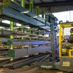 Combilift COMBI-MR4 forklift reaching to grab steel materials in warehouse.