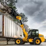 JCB TM-320 articulated telescopic handler moving giant tree log over semi container.