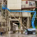 Genie Z-60 FE Articulating Boom Lift lifting operator towards the top of a building.