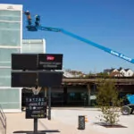 Genie S-60 FE telescopic boom lift extended, with workers in bucket.