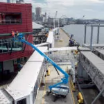 Genie S-60 J telescopic boom lift raising workers to repair the side of a dock building.