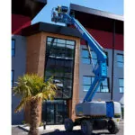 Genie S-60 FE telescopic boom lift raising workers to the top of a building.