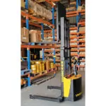 TASK Taipan straddle stacker grabbing pallet off a shelf in a warehouse.