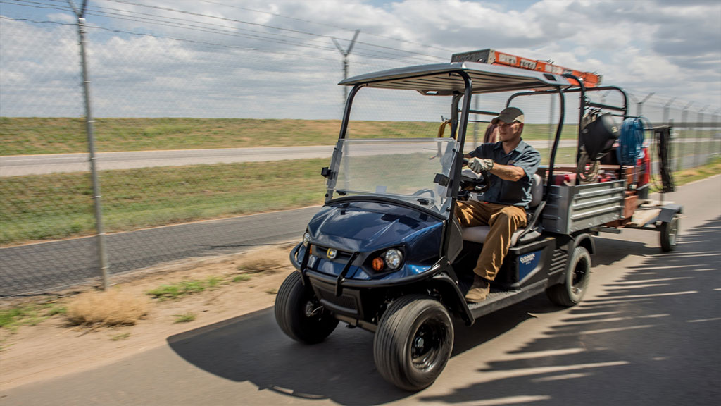Cushman Hauler 1200 Utility Vehicle with trailer driving on path.