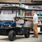Man loading tools and materials into Cushman Hauler 1200 Utility Vehicle cargo bed.