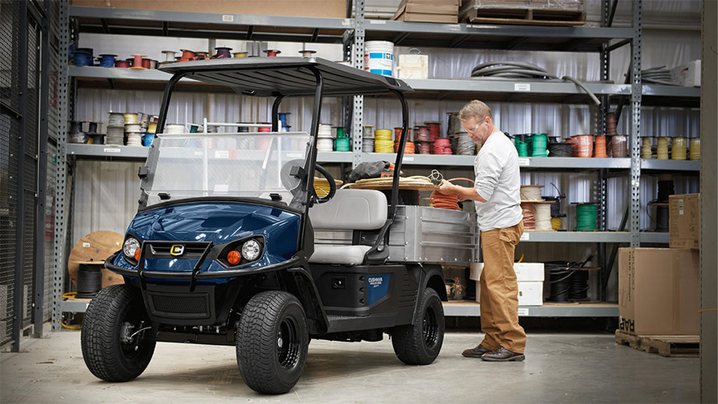 Man loading tools and materials into Cushman Hauler 1200 Utility Vehicle cargo bed.