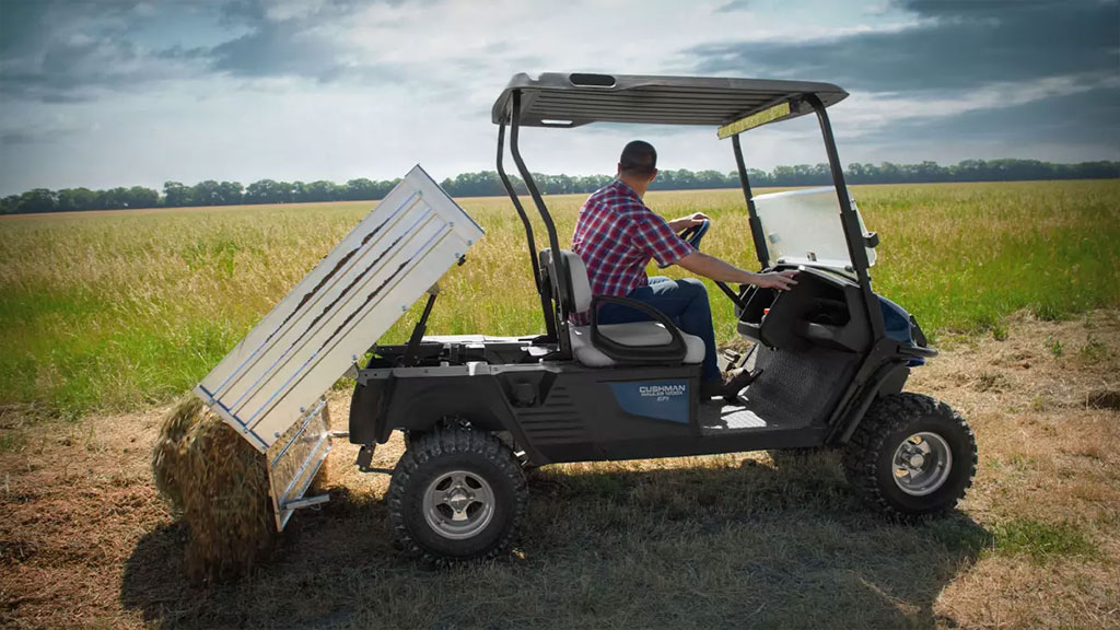 Cushman Hauler 1200X utility vehicle lifting bed to dump out dirt.
