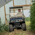 Cushman Hauler 1200X utility vehicle driving through greenhouse with rough terrain.