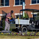 Worker getting materials out of Cushman Hauler Pro utility vehicle cargo bed.