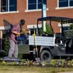 Worker getting materials out of Cushman Hauler Pro utility vehicle cargo bed.