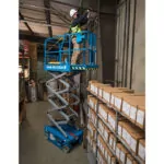 Repairman raised in bucket of Genie GS-1932m scissor lift.