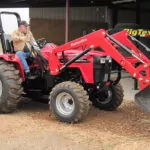 Mahindra 4550 4WD Tractor with bucket attachment driving on dirt road.