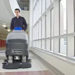 Walk-behind Advance SC800 scrubber cleaning hallway floors.