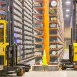 Combilift COMBI-AGT autonomous forklift trucks in narrow aisle warehouse.