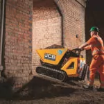 JCB HTD-5E electric dumpster driving up dirt hill at worksite.