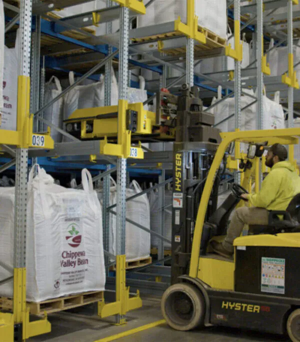Hyster lift truck placing pallet shuttle on warehouse racking.
