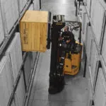 Bendi B40AC narrow aisle forklift grabbing pallet of materials off warehouse aisle racking.