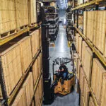 Bendi B40AC-HL lifting pallet off warehouse racking in narrow aisle.